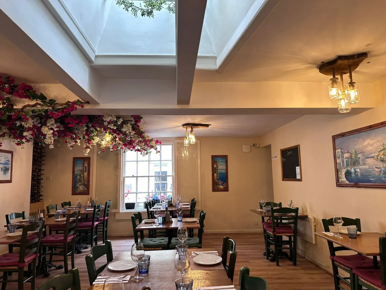 Wooden tables, green chairs and warm jar lights in the Jars Meze dining room